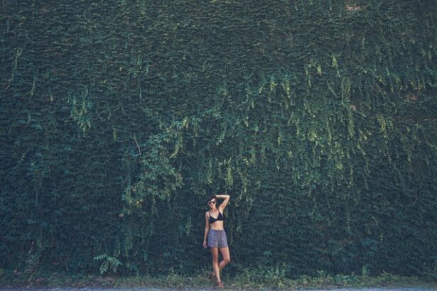 A woman in front of a tall wall covered in leaves and plants